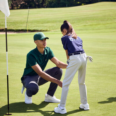 Bild vergr&ouml;&szlig;ern: Ein Golflehrer schult ein Kind am Abschlag.